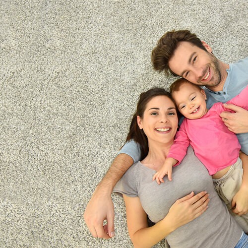 Happy family lying on carpet flooring | Country Carpet & Furniture